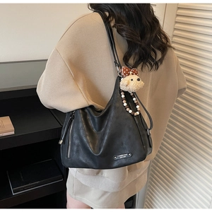 Détail du grand sac hobo noir en cuir souple avec breloque ours mignon sur la bandoulière