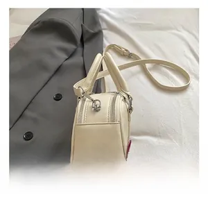 Detail view of the cream leather bag showing silver metal D-rings and dual zipper closure