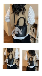 Macro detail of black lychee grain leather bucket bag with metal buckle and plush charm