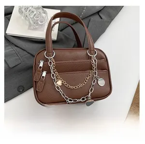 Close-up of brown lychee grain leather briefcase with decorative gold and silver metal chains
