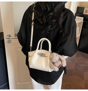 Close-up of white lychee pattern leather tote bag with silver buckle and plush rabbit charm