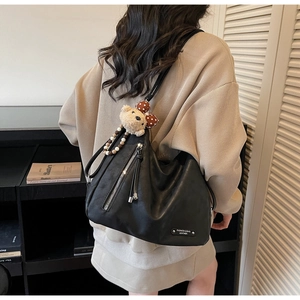 Gros plan du sac bandoulière noir en cuir PU avec breloque ours et plaque en métal