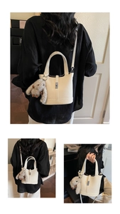 Close-up of white lychee-grain leather bucket bag with metal clasp and plush rabbit charm
