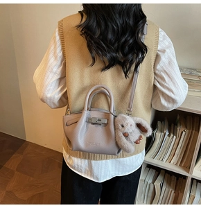 Detail view of purple leather pleated bag with metal turn-lock and plush bunny charm