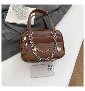 Detail of brown lychee texture Boston bag with dual zippers and decorative heart metal chains