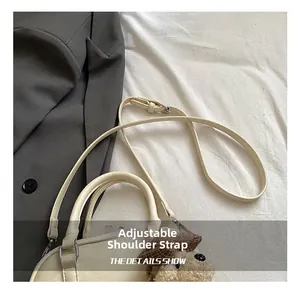 Detail of adjustable strap and plush bear charm on minimalist cream shoulder bag