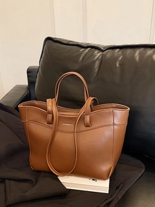Stylish brown leather tote bag with sturdy handles and a metal logo on the front