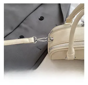 Detail showing high-quality silver metal hooks and zippers on a cream leather handbag