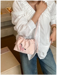 Detail of light pink drawstring bag featuring a cute plush animal embroidery and soft fabric