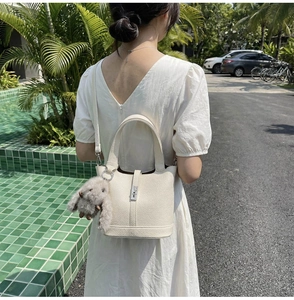 Detail of off-white bucket bag with leather texture and cute rabbit charm strap detail