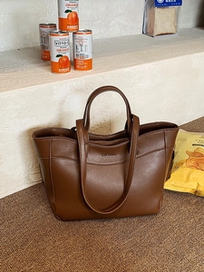 Brown leather tote bag with patchwork design and shoulder straps in warm natural lighting