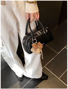Detail view of black faux leather mini bowling bag with cute plush bear charm