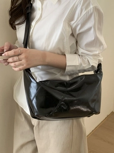 Chic black glossy leather hobo shoulder bag with wide strap in a minimalist style
