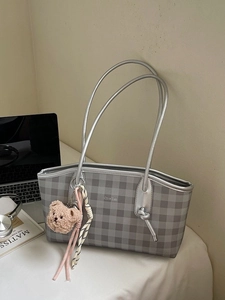 Gray textured tote bag with silver straps, plush bear charm and office desk items