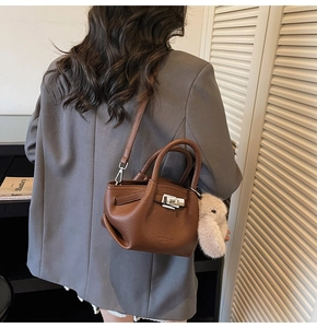 Detailed back view of a brown pebbled leather tote with a plush rabbit charm and strap