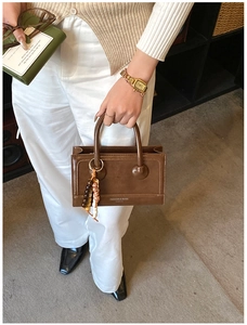 Detailed view of a vintage brown handbag with wooden bead tassel and polished finish