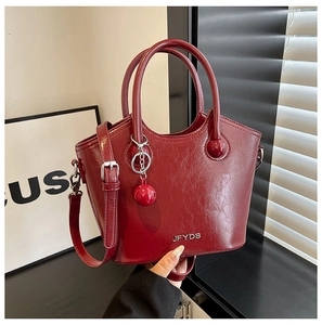 Macro detail of wine red bucket bag in glossy wrinkled leather with metallic JFYDS logo