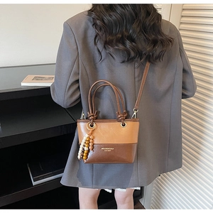 Close-up of stylish patchwork handbag featuring warm khaki and dark brown PU leather panels