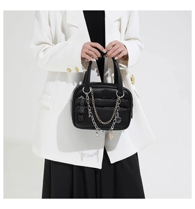 Close-up of black lychee grain leather handbag featuring decorative gold and silver chains
