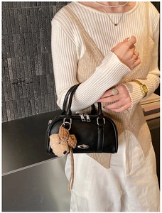 Close-up of black leather Boston bag featuring silver hardware and a cute plush charm