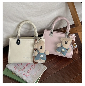Detail of elegant tote bags with woven handles and cute plush bear pendants in warm setting