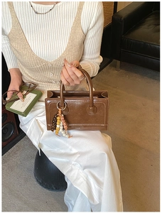 Detailed macro view of brown patent leather bag with gold rings and beaded charms