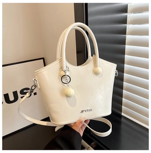 Detail of white bucket bag with silver JFYDS logo and round ball pendant charm
