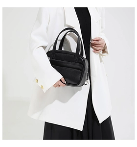 Close-up detail of the black lychee pattern texture and zipper pocket on the Boston bag