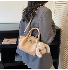 Detail of apricot pebbled leather tote with silver twist lock and plush rabbit charm