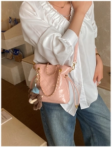 Detail of pink quilted crossbody bag with gold chain and plush bear charm