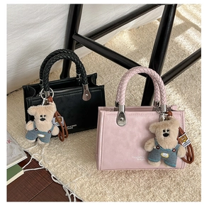 Detail of woven handles on pink and black crossbody bags with cute bear charms