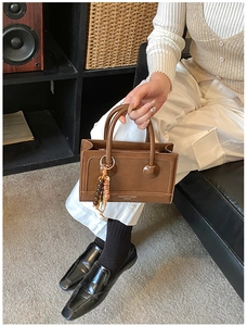 Close-up of a vintage brown handbag with ethnic bead charms and fashion brand logo