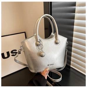 Detailed macro view of silver metallic bucket bag with logo and spherical charm accessory