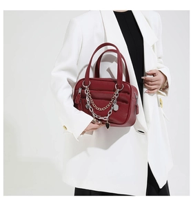 Detailed macro view of dark red lychee leather texture and metallic heart charms on handbag