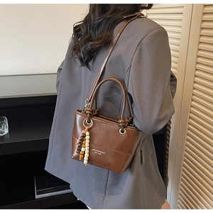 Detail of vintage brown leather bucket bag showing adjustable strap and colorful wood beads