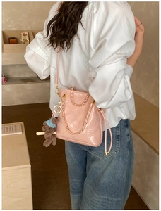 Detail of pink quilted bucket bag with gold chain strap and cute teddy bear charm