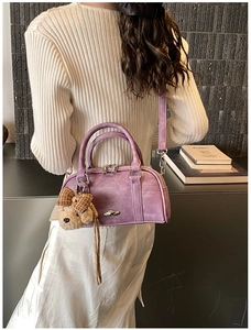 Detail showing lavender suede Boston bag with a cute teddy bear charm on shoulder