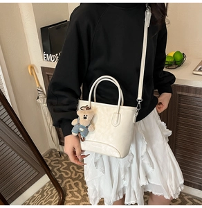 White pebbled leather bucket bag with cute bear charm and long shoulder strap
