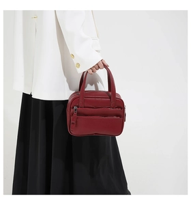 Detail of burgundy lychee grain leather tote bag with dual zippers held by a model
