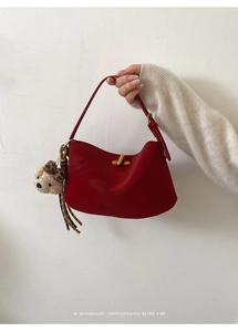 Dettaglio borsa a tracolla in pelle rossa con chiusura a scatto e orsetto peluche