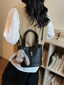 Black litchi grain leather bucket bag with metal lock and plush rabbit pendant
