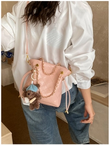 Pink quilted leather bucket bag detail with golden chain and cute brown bear charm accessory