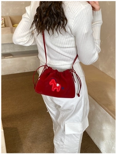 Detail of red velvet drawstring bag with elegant horse embroidery and thin strap