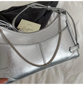 Détail du sac argenté métallisé avec texture craquelée et bandoulière en chaîne