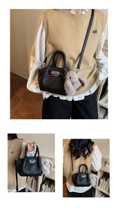 Detail view of black textured bucket bag with silver twist lock and plush rabbit charm