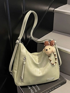 Sac à bandoulière vert clair texturé avec charme d'ours en peluche sur marches