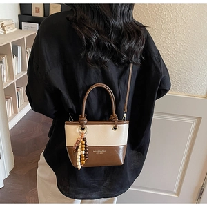 Detail of a chic cream and brown bucket bag with decorative beads on a model background