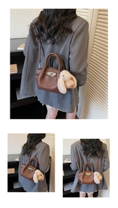 Detail view of brown textured leather tote with silver metal twist lock and bunny charm