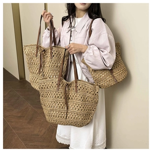 Detail of hand-woven straw tote bag with brown leather handles and hollow mesh texture