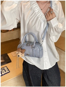 Light blue Boston bag with plush bear charm and checkered bow shown on a model